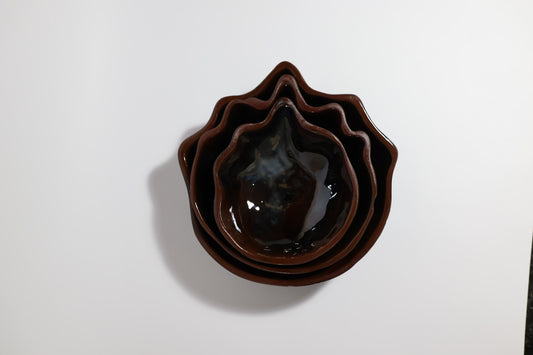 Top view of three uDengezi Handmade Black ceramic nesting bowls with organic pointed rims and brown glazed interiors