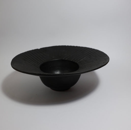Matte black wide-rim ceramic bowl side view showing deep centre well and pedestal base